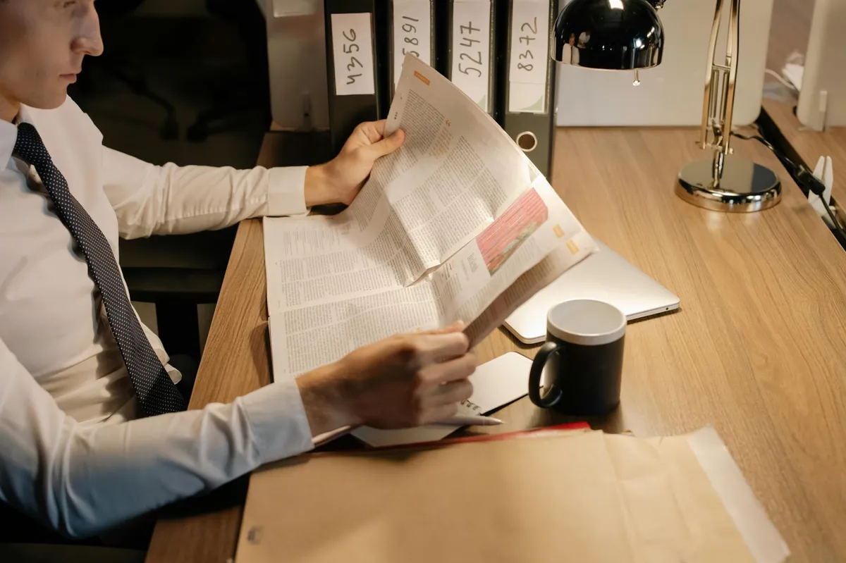 Pesquisadora lendo e organizando documentos em mesa com textos sublinhados e anotações