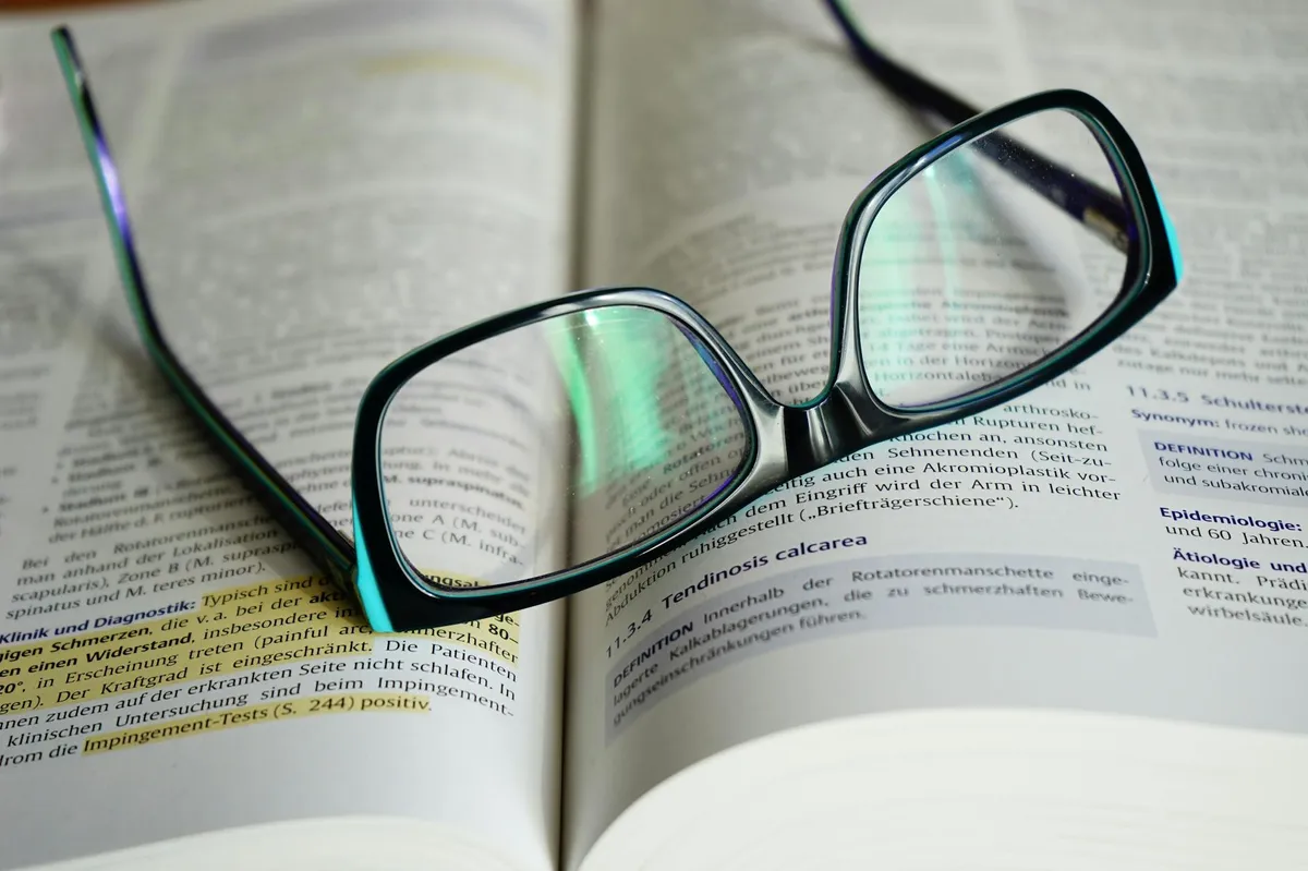 Pesquisadora lendo e anotando textos acadêmicos em mesa de trabalho