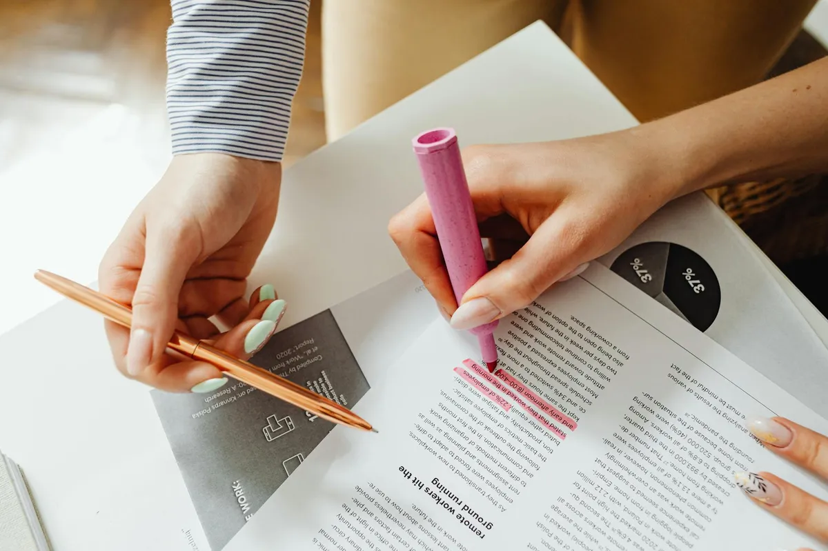 Pesquisadora analisando textos e documentos em mesa de trabalho acadêmico