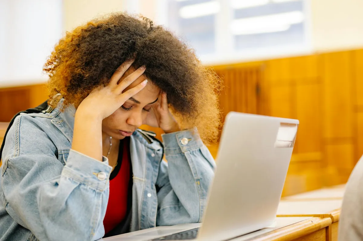 Estudante de mestrado olhando para tela de computador com expressão de estresse