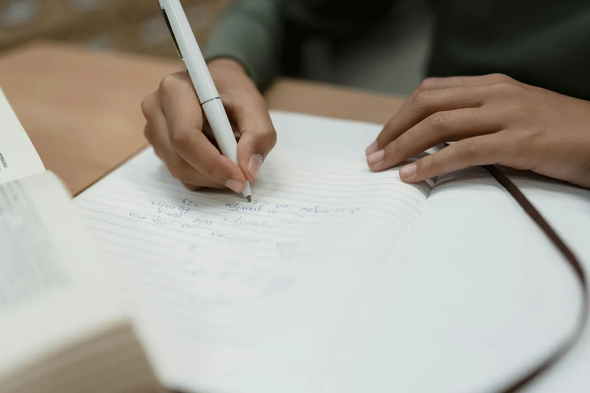 Pesquisadora escrevendo em caderno de campo com notas reflexivas