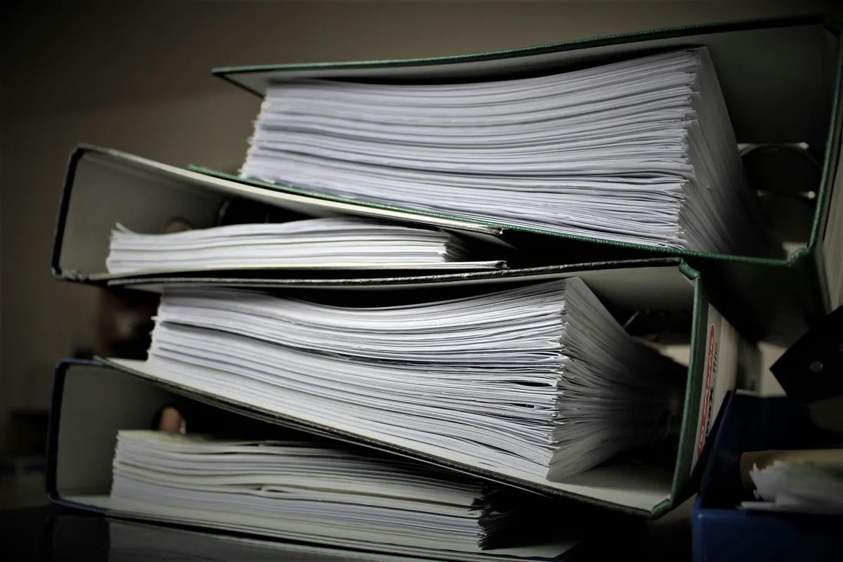 Pesquisadora lendo documento de política educacional sobre mesa com caderno de anotações