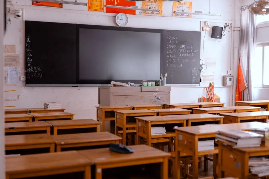 Livros didáticos e cadernos sobre mesa em sala de aula, representando pesquisa em educação.