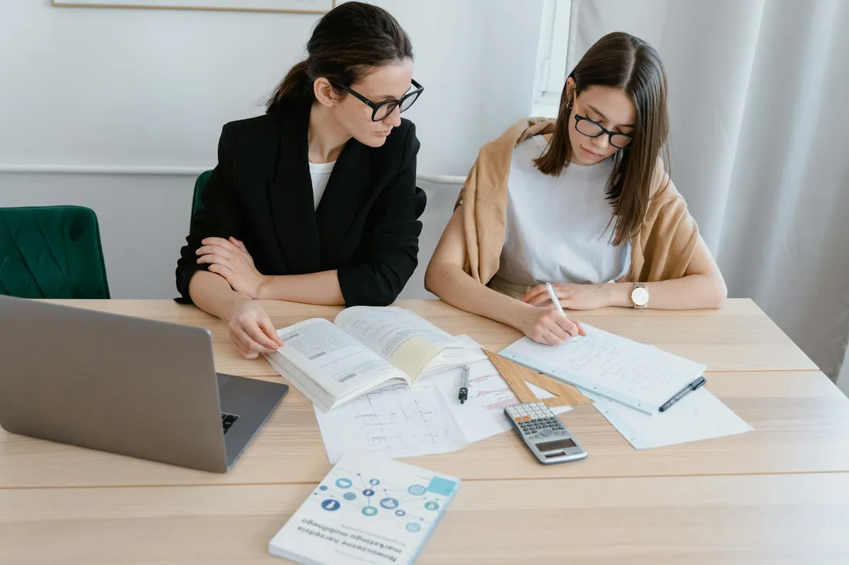 Duas pessoas em reunião de trabalho: uma com postura colaborativa, outra com postura fechada