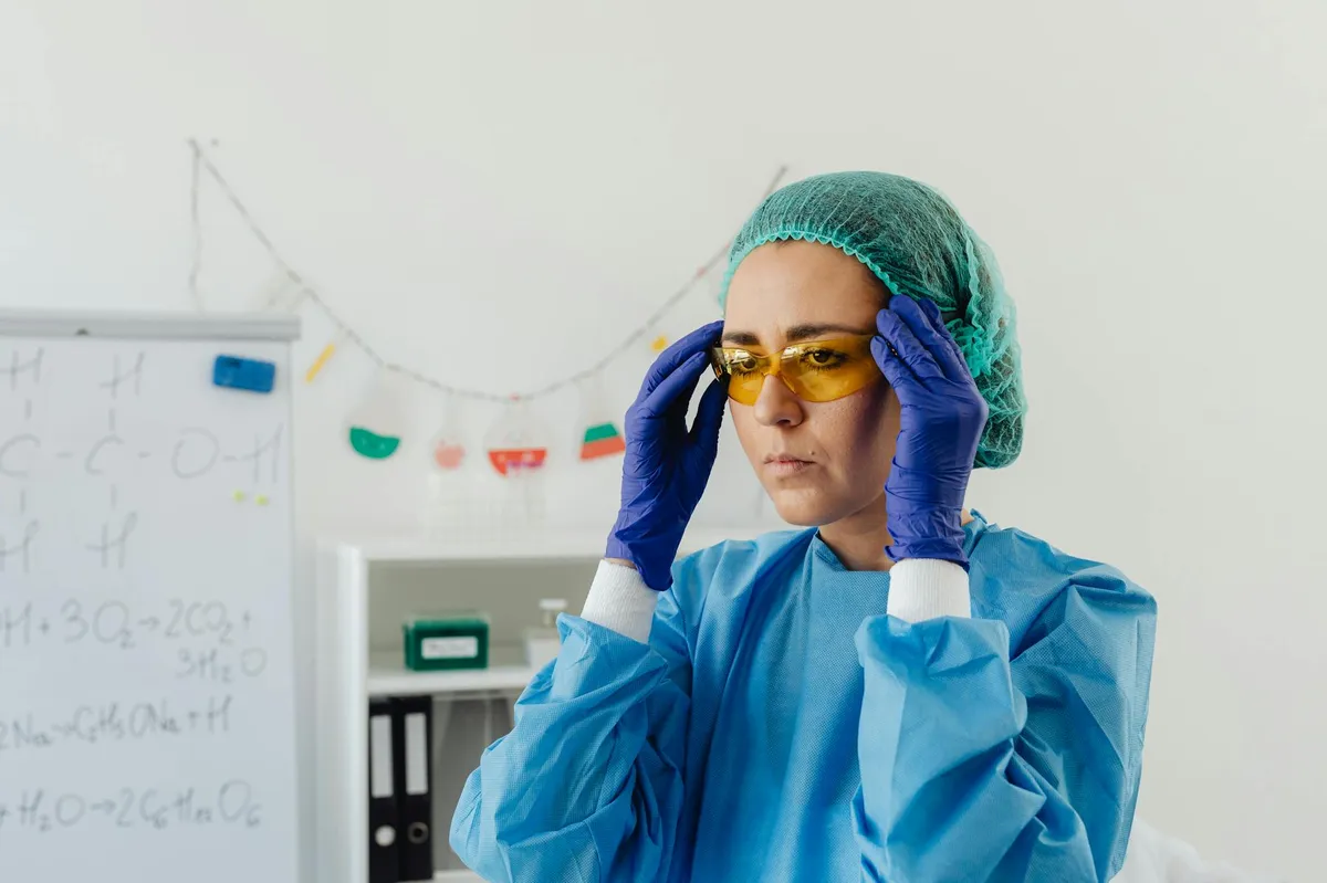 Pesquisadora trabalhando em laboratório acadêmico com expressão de cansaço