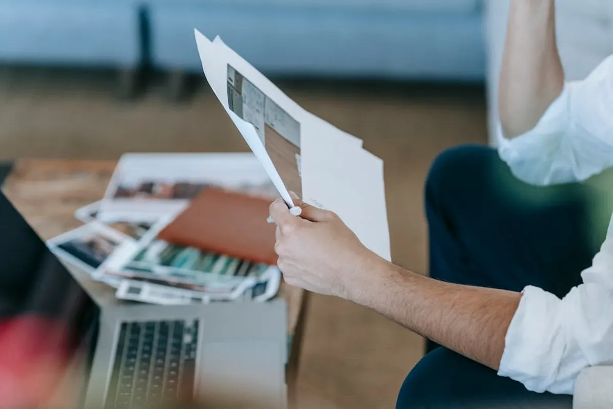 Pessoa com notebook e documentos, planejando negócio como MEI, representando empreendedorismo na pós-graduação