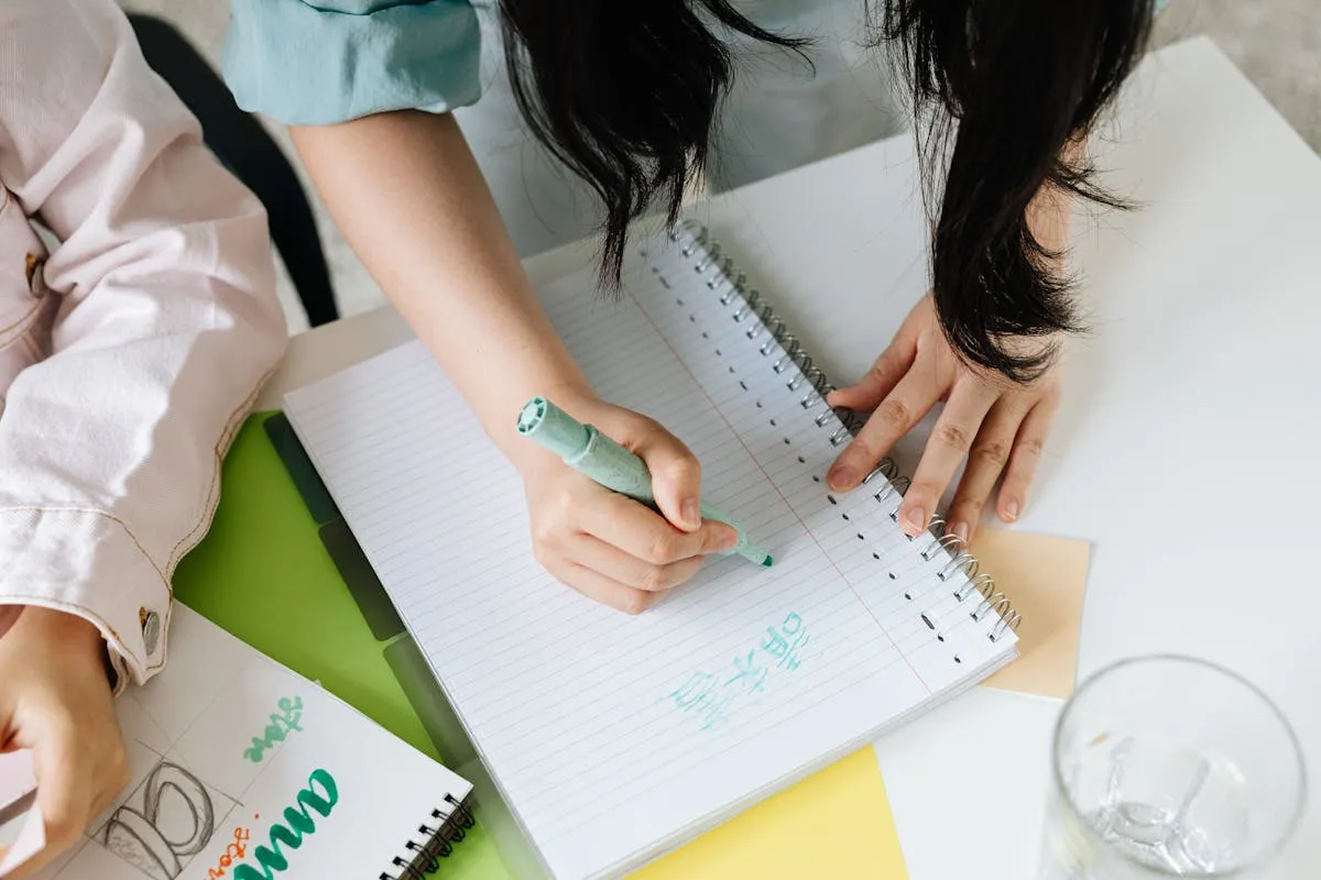 Mesa de trabalho com caderno aberto, anotações e esboços de texto acadêmico