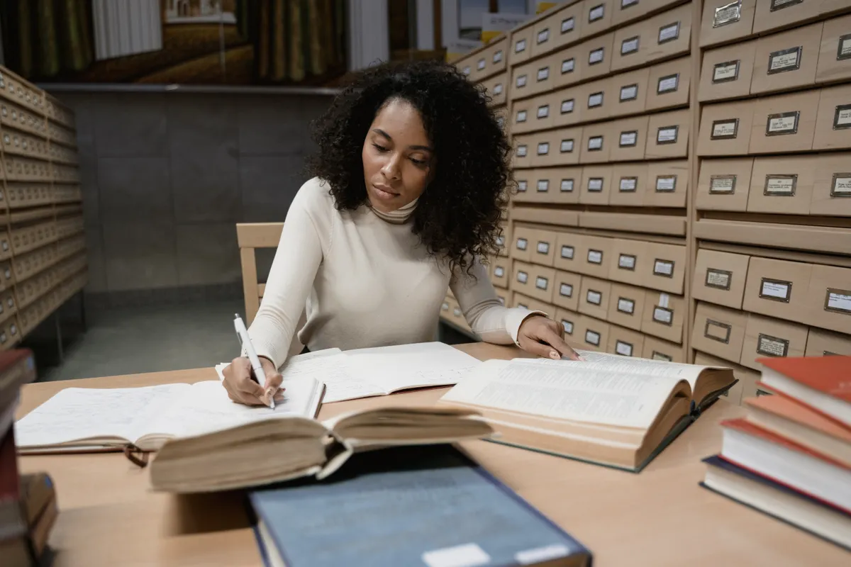 Pesquisadora revisando texto no notebook com aba de chat de IA aberta ao lado