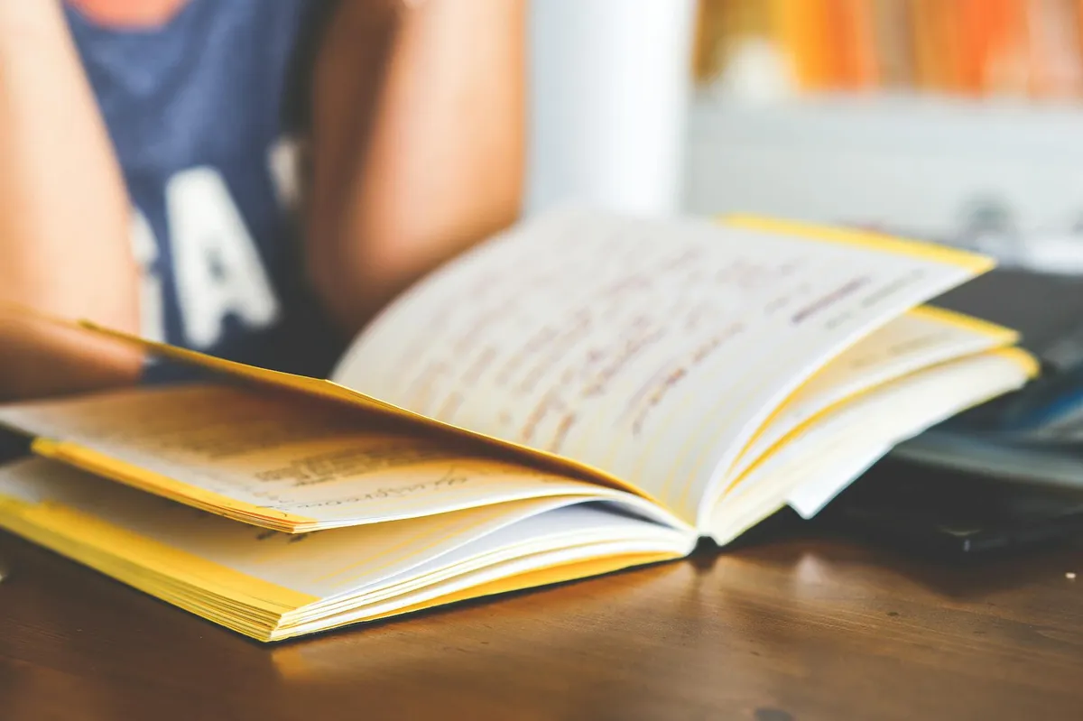 Estudante lendo livro acadêmico com marcações e anotações