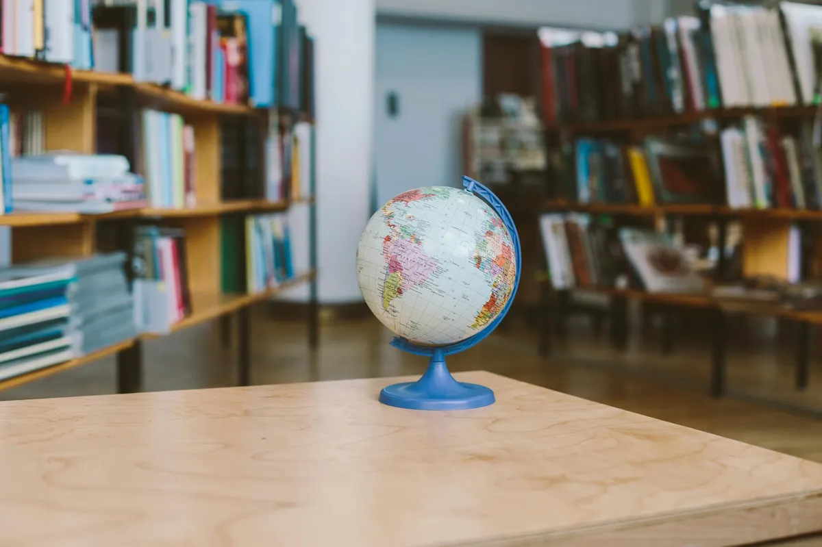Globo terrestre sobre mesa com livros acadêmicos ao fundo