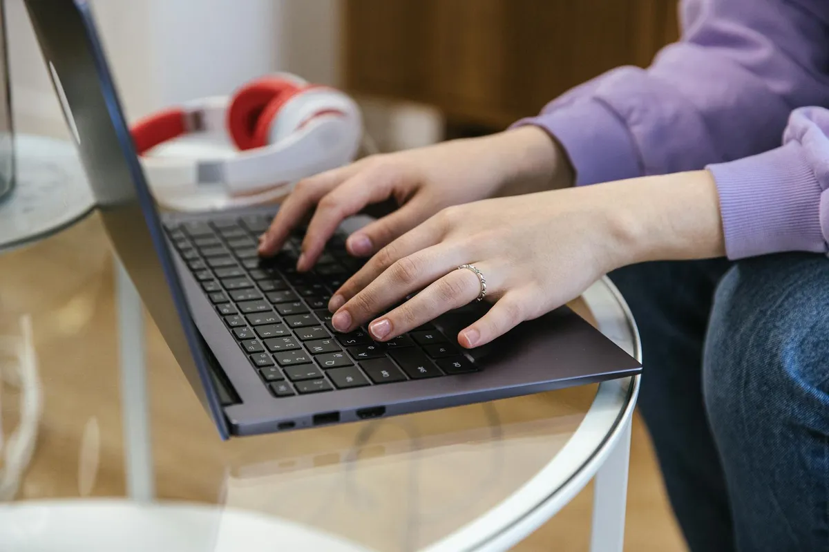 Pessoa digitando e-mail em notebook com anotações ao redor