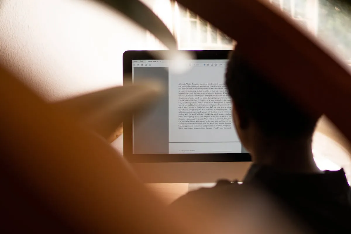 Pessoa lendo texto em tela de computador com expressão analítica