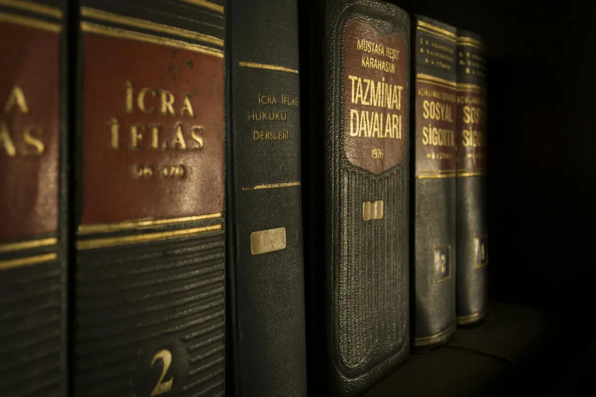 Livros jurídicos empilhados sobre mesa com óculos e caneta