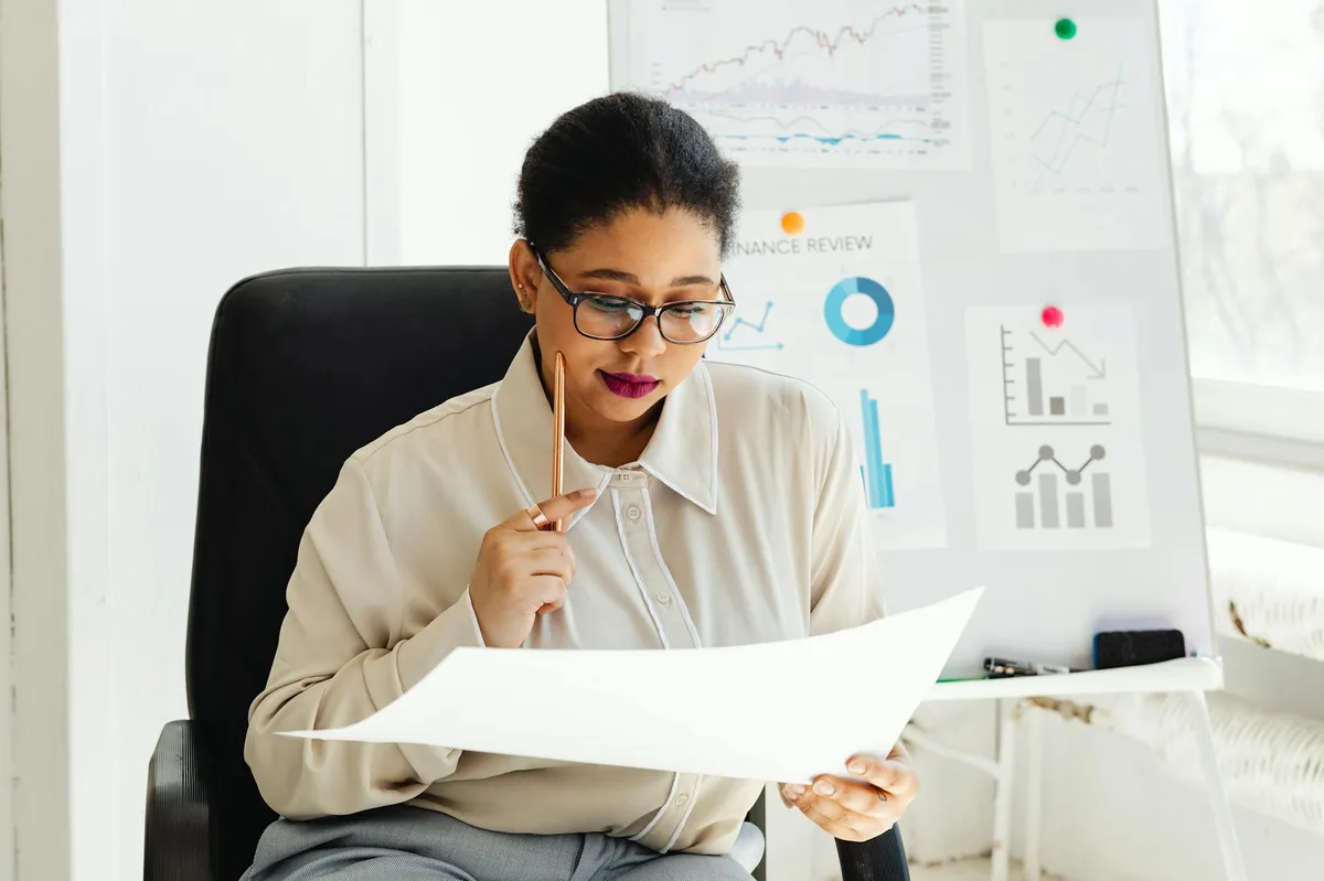 Pessoa analisando documentos e tomando notas em uma mesa de trabalho