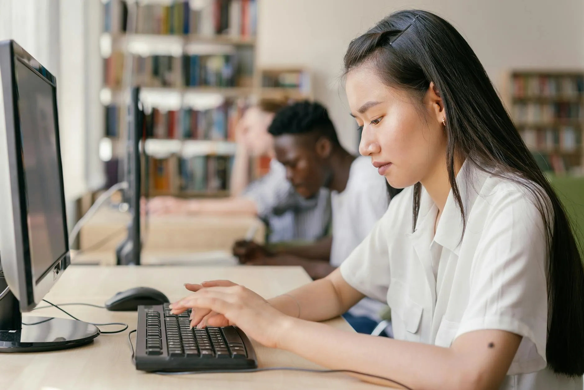 Pesquisadora digitando texto acadêmico em inglês em computador em ambiente universitário