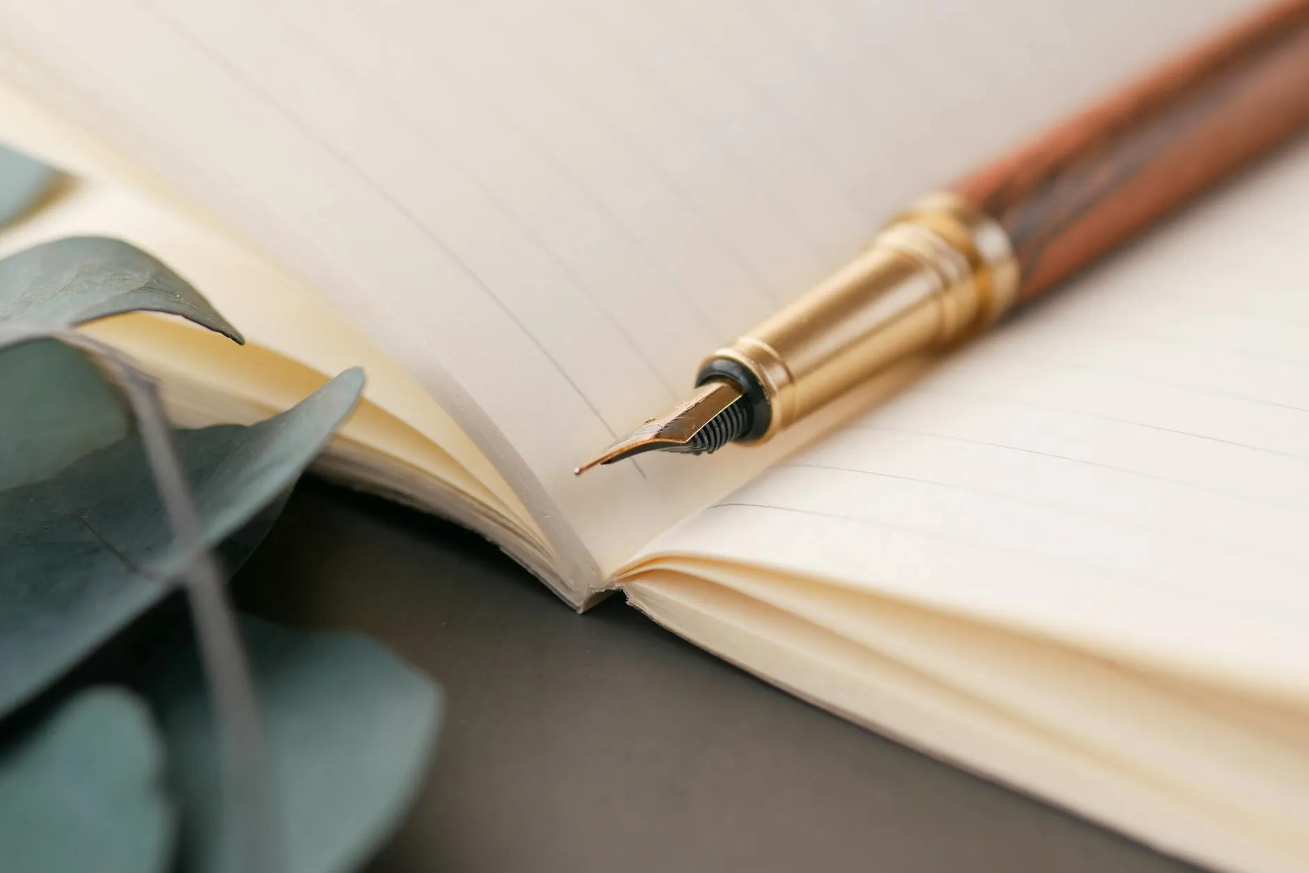 Caderno com folha em branco e caneta sobre mesa de madeira