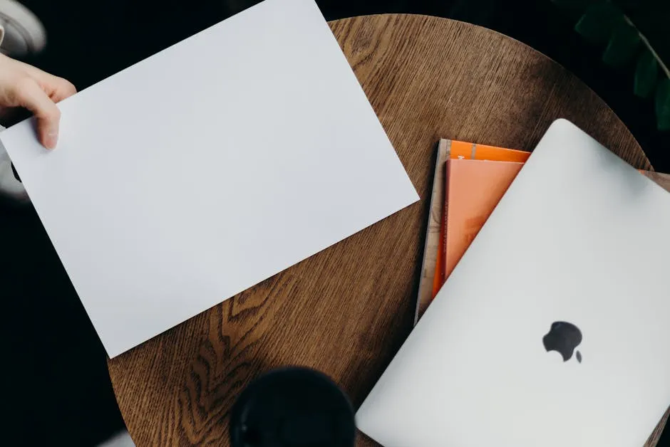 Pessoa escrevendo em notebook aberto sobre mesa organizada, com xícara de café ao lado