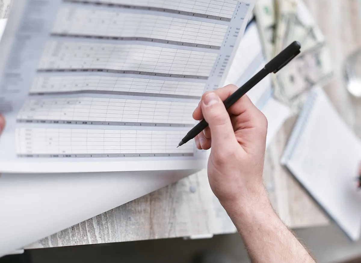 Mesa de trabalho com planilha, calculadora e caderno de anotações para planejamento financeiro de pesquisa.