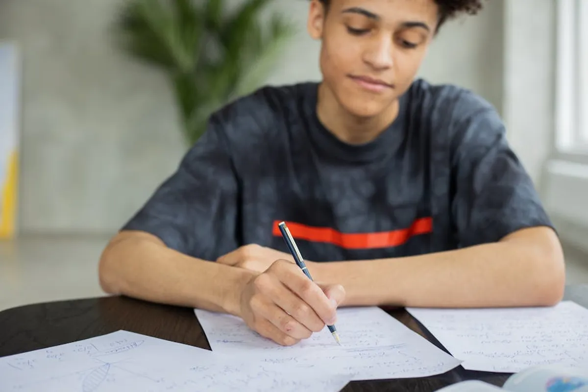 Pessoa estudante escrevendo em caderno em biblioteca universitária