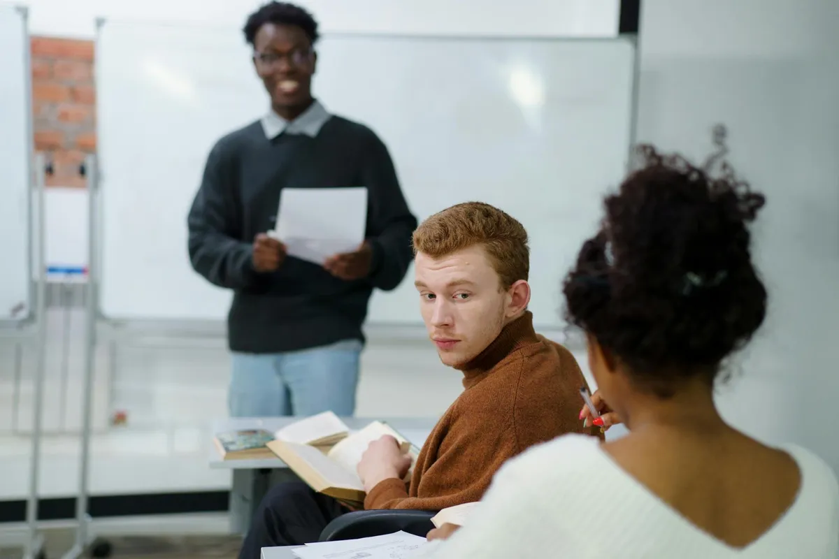 Estudante apresentando seminário em sala de aula para colegas e professora