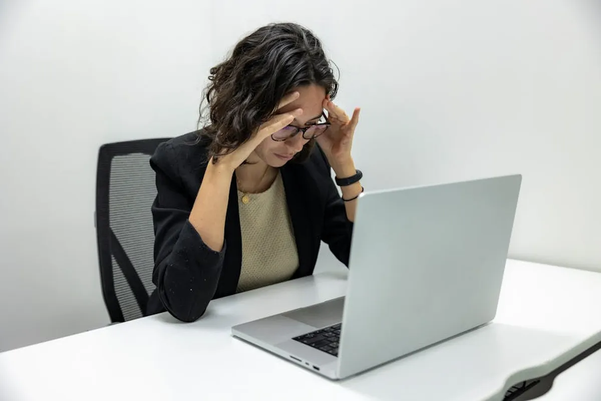 Pesquisadora com expressão concentrada diante de papéis e computador