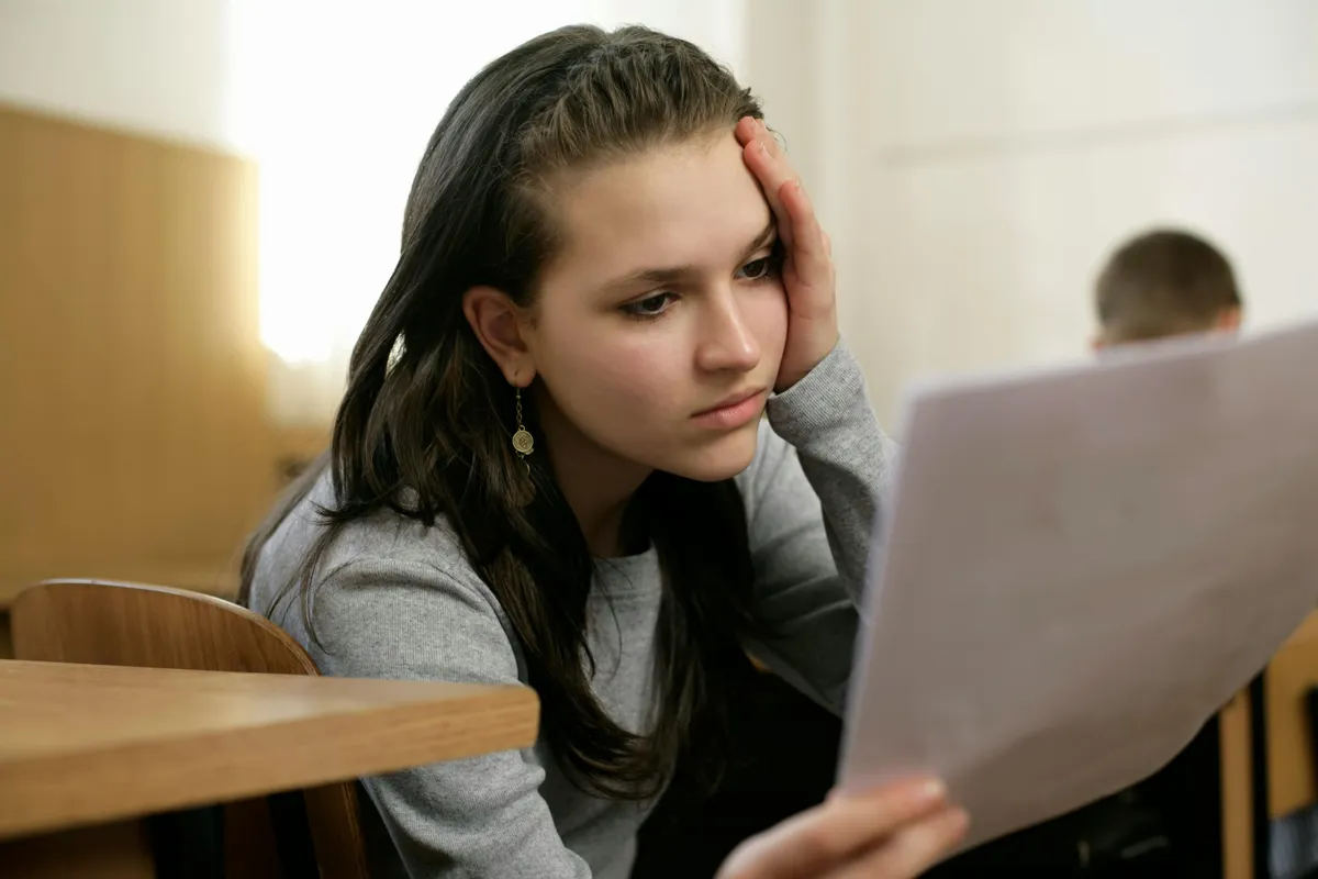 Pesquisadora lendo e fazendo anotações em texto acadêmico sobre mesa de estudo