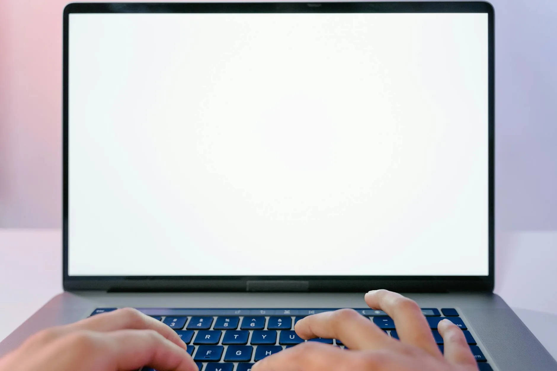 Pesquisador olhando para tela em branco do computador com caderno aberto e caneta na mão