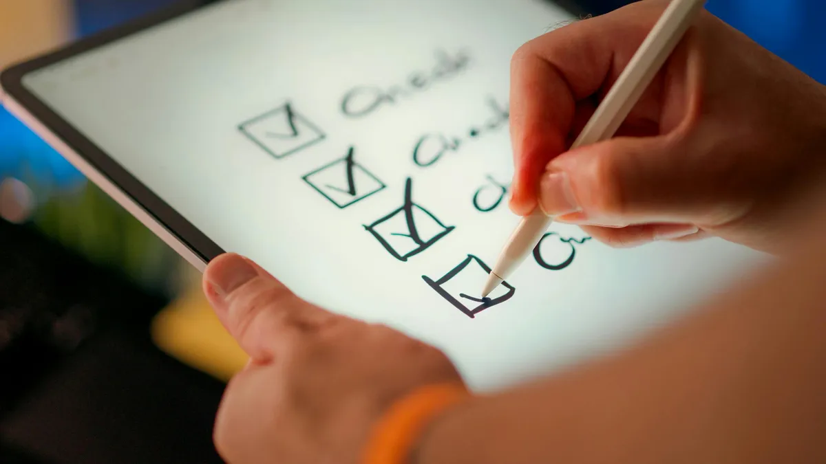 Pesquisadora analisando questionário em papel e computador com planilha de dados