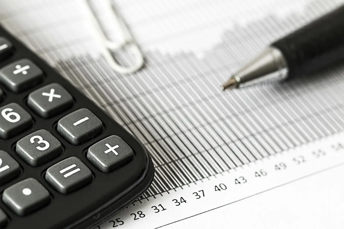 Tesoura cortando papel com gráfico de queda orçamentária