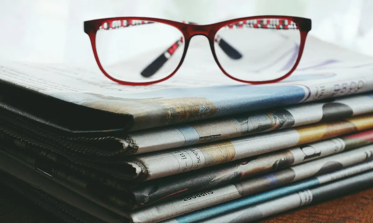 Pilha de revistas científicas e laptop com artigo aberto representando publicação acadêmica