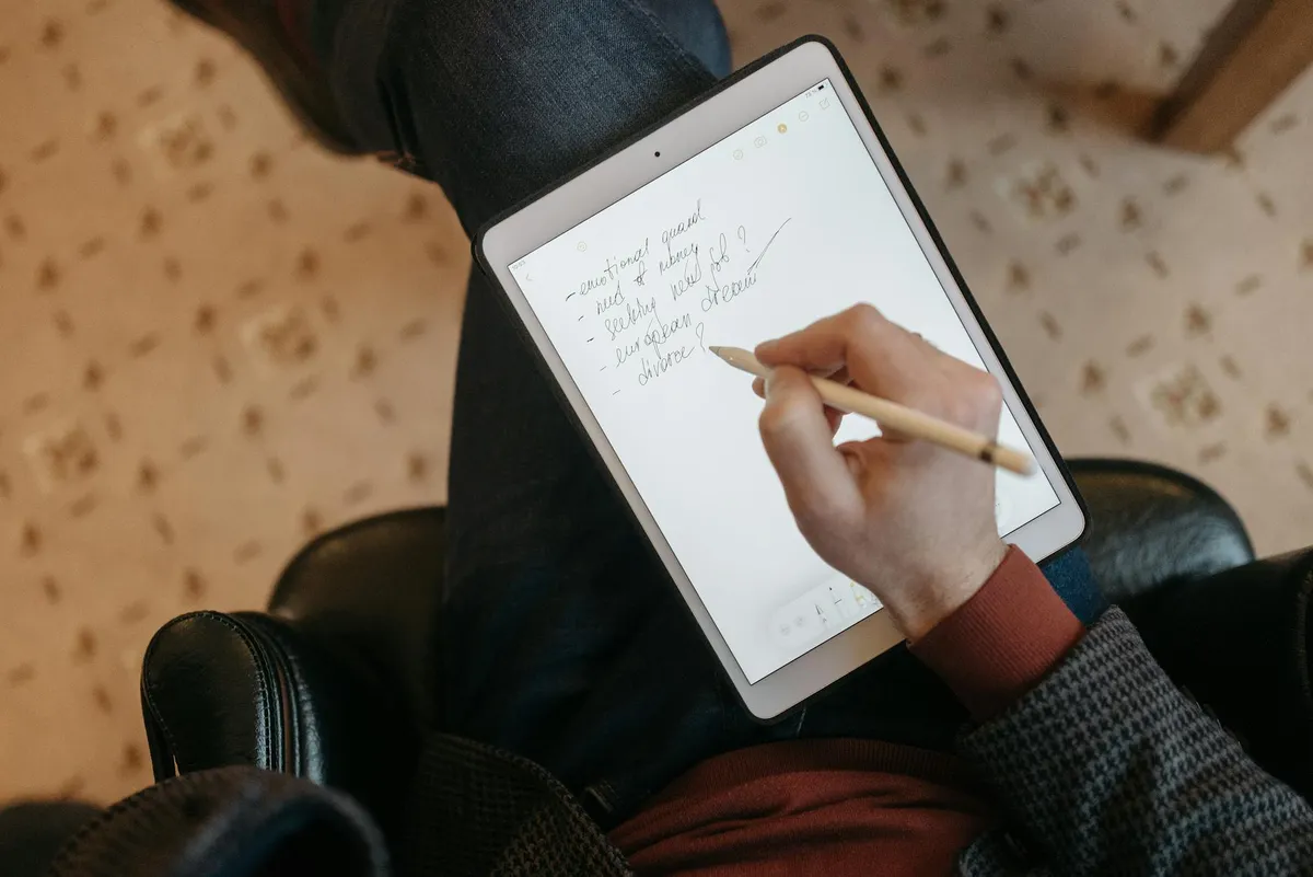 Pessoa revisando texto acadêmico em tablet com caneta digital, representando revisão com tecnologia
