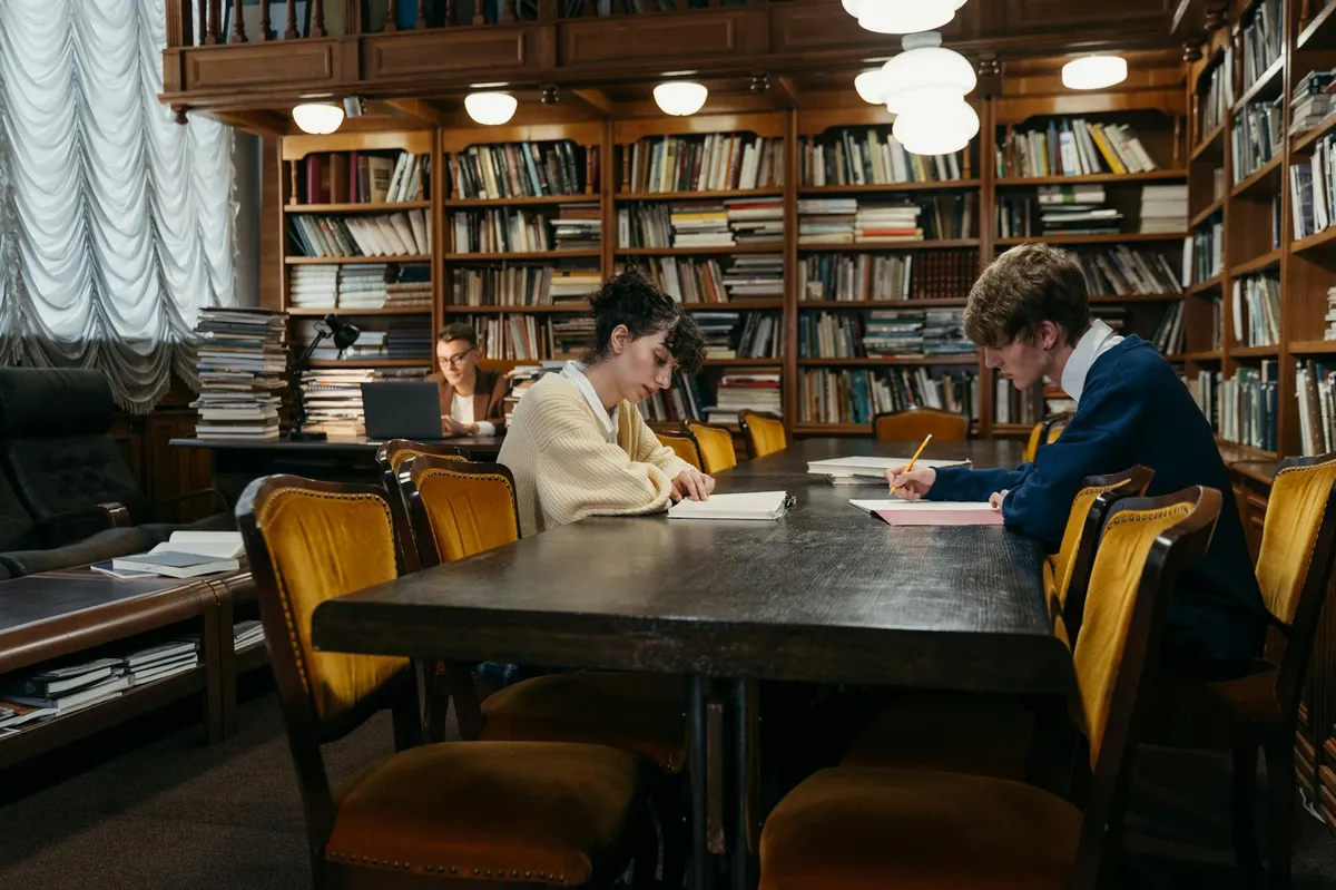 Biblioteca universitária com estudantes pesquisando, simbolizando o ambiente acadêmico brasileiro