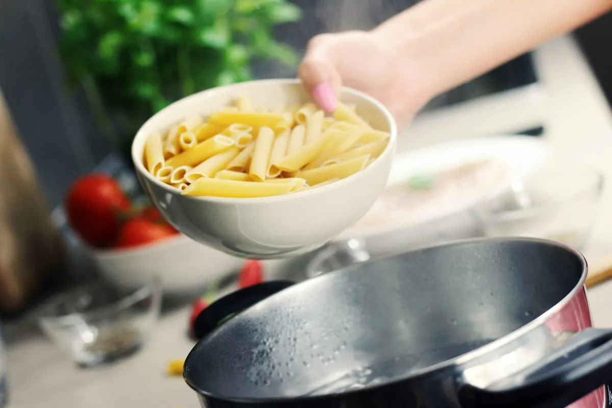 Pessoa preparando refeição simples na cozinha com caderno de anotações ao lado