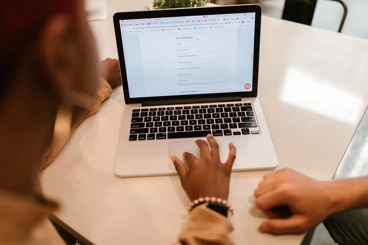 Pessoa usando computador para preencher formulário online com documentos ao lado