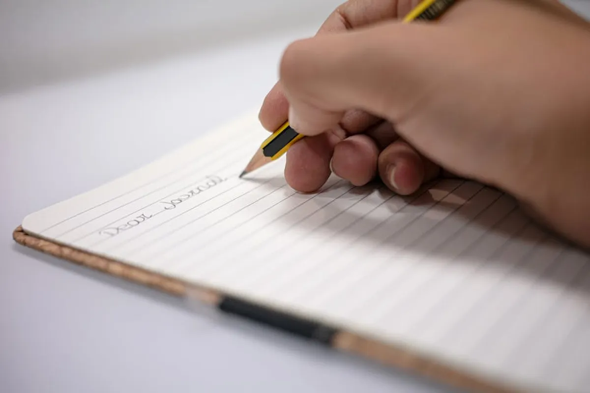 Caderno aberto com caneta ao lado, representando a escrita de uma dedicatória acadêmica