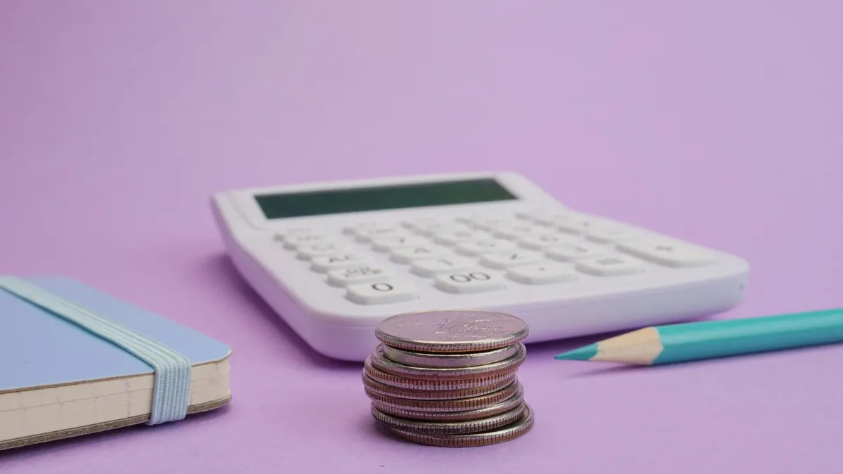 Calculadora e notas de dinheiro sobre mesa, representando cálculos financeiros de bolsa de pesquisa