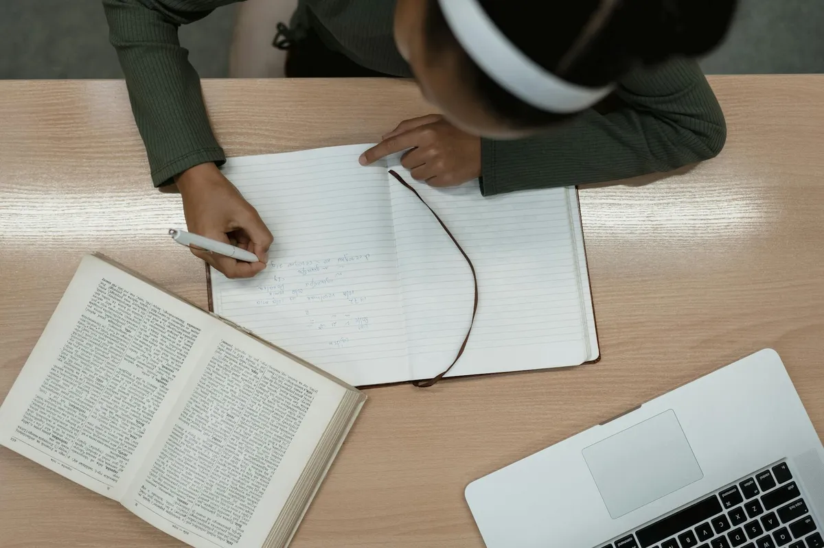 Estudante lendo e anotando em livro acadêmico