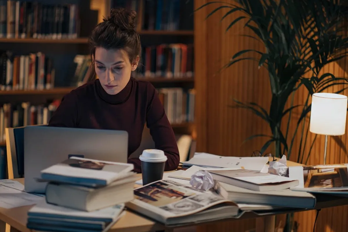 Profissional em ambiente de trabalho com documentos e computador, estudando para mestrado