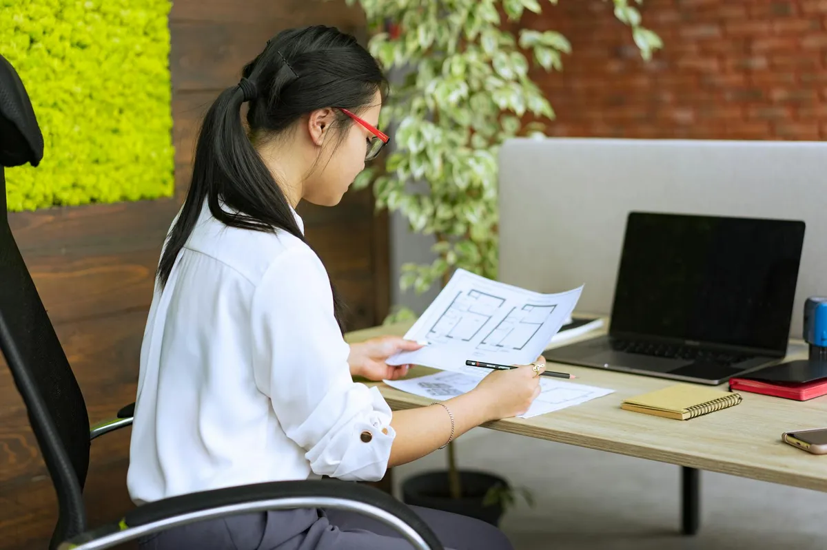 Profissional em transição de carreira estudando com documentos e notebook em mesa