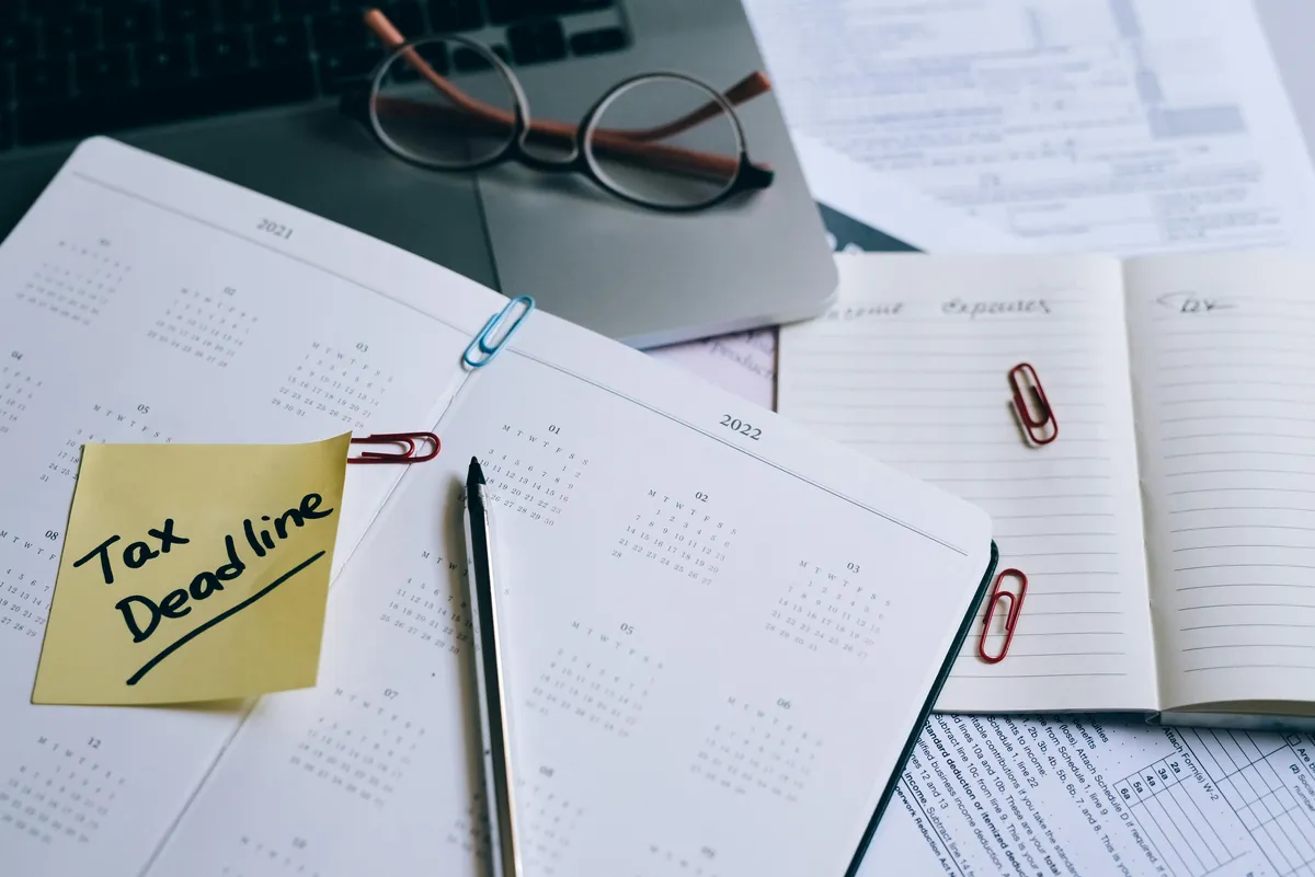 Calendário e relógio em cima de mesa com livros acadêmicos representando pressão de prazo