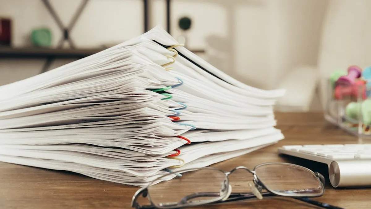 Pilha de documentos acadêmicos impressos sobre mesa de escritório