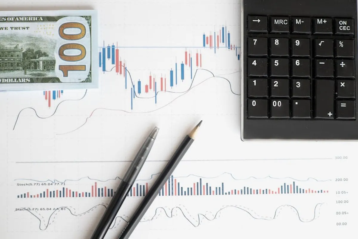 Gráficos e tabelas financeiras sobre mesa com calculadora e notebook