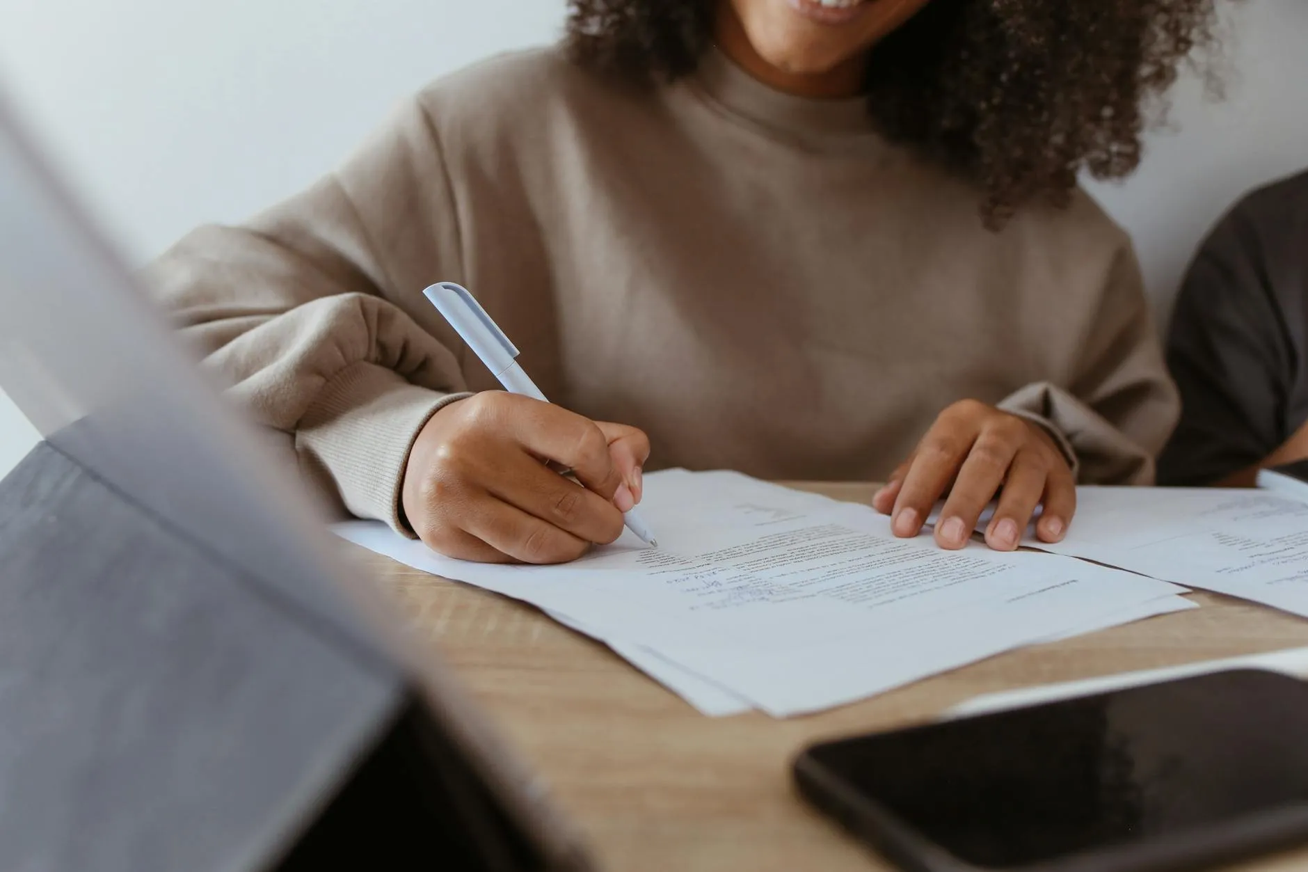 Pessoa revisando texto acadêmico em papel com caneta vermelha marcando trechos
