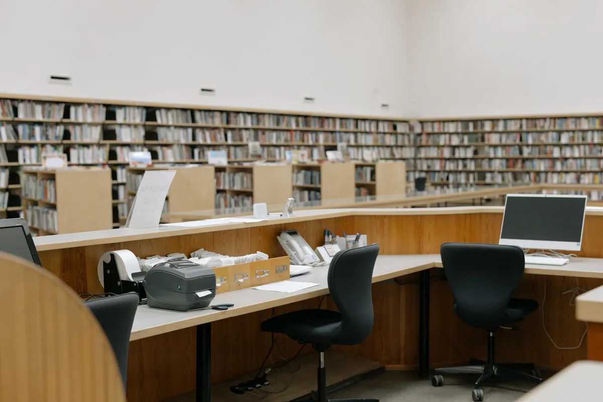 Estudante organizando referências bibliográficas no computador com livros ao redor