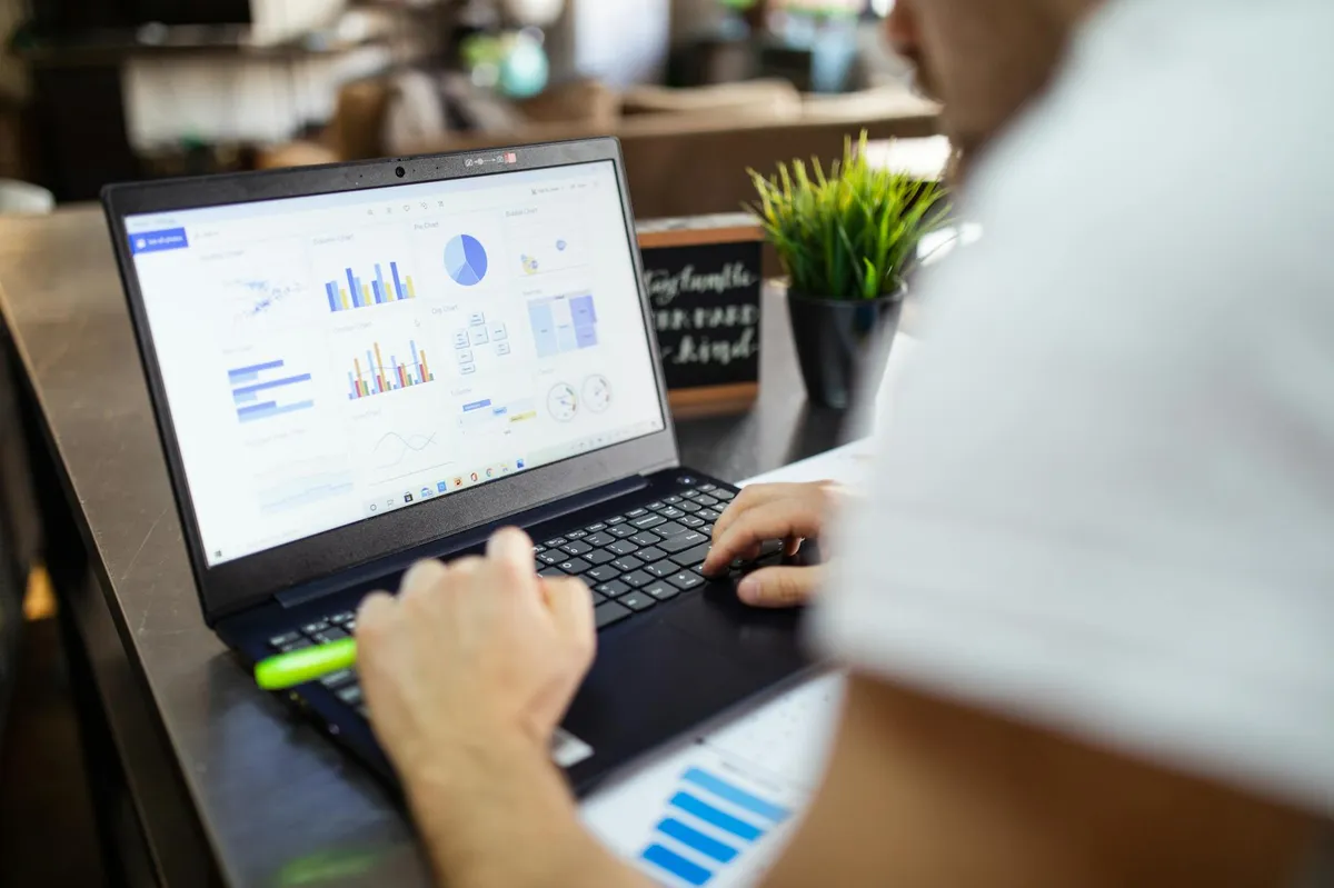 Pesquisadora analisando dados estatísticos em computador com gráficos