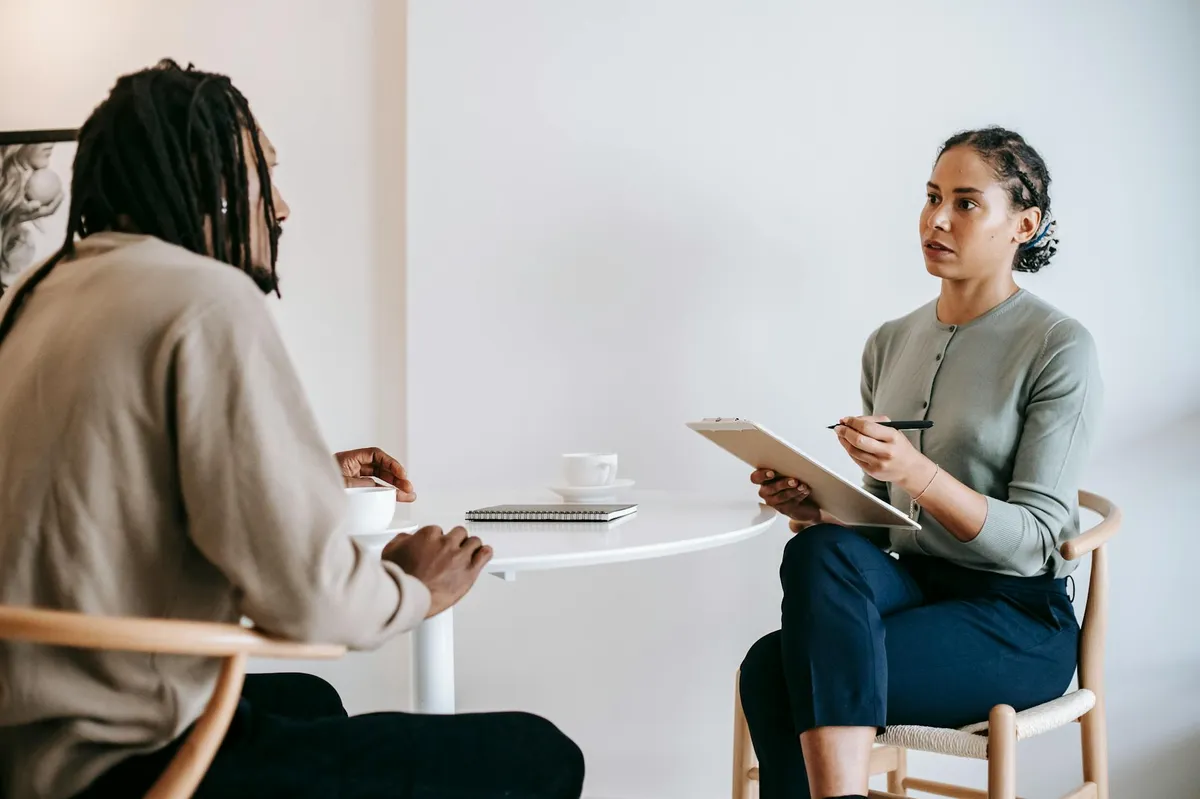 Pesquisadora em entrevista aprofundada tomando notas detalhadas em ambiente de trabalho corporativo