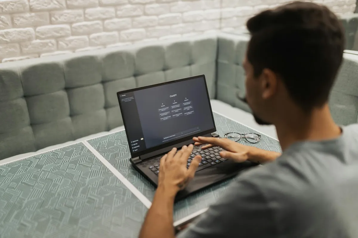 Pessoa digitando em laptop com interface de inteligência artificial na tela