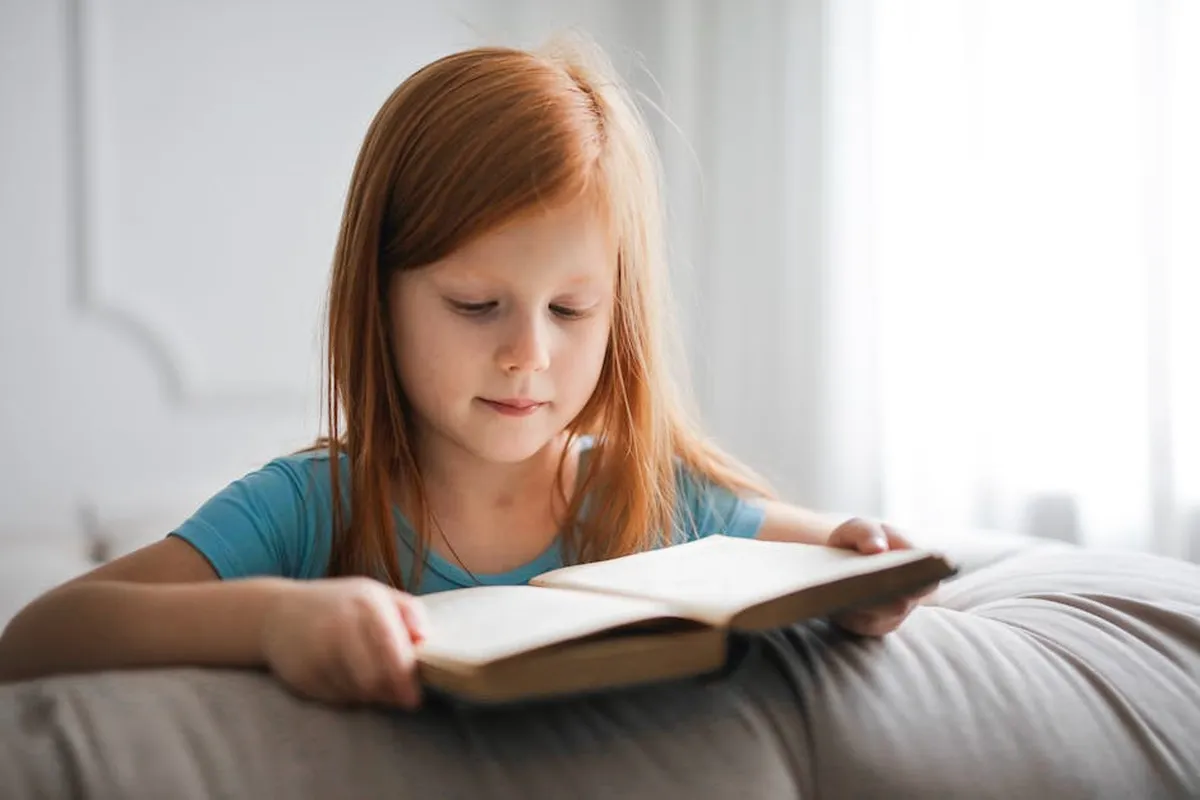 Criança lendo um livro com luz suave ao fundo, representando alfabetização