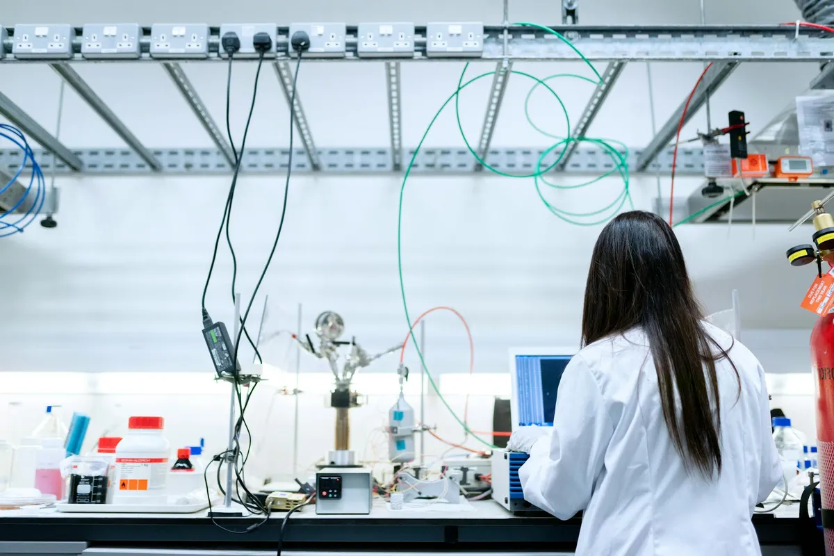 Engenheiro pesquisador em laboratório com equipamentos e tela de computador com dados técnicos