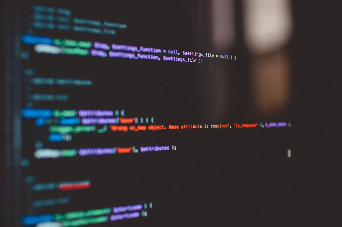 Dois computadores lado a lado com código aberto e interface de IA em telas